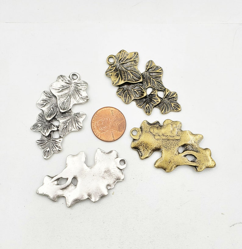 May include: Four metal leaf charms in silver and gold tones. The charms are in the shape of ivy leaves and are perfect for jewelry making or crafting.