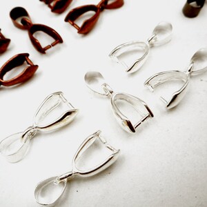 May include: A set of silver and copper-toned pendant clasps. The clasps are designed to hold a pendant or charm. They are a popular choice for jewelry making.