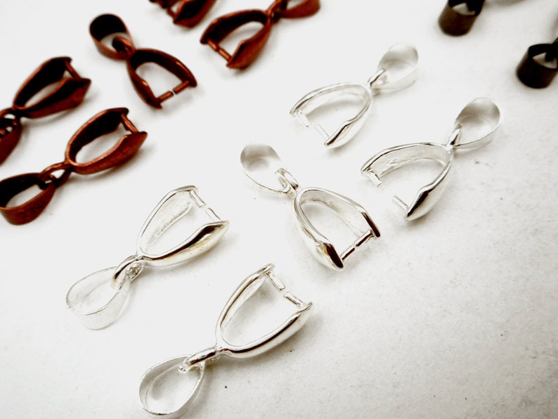 May include: A set of silver and copper-toned pendant clasps. The clasps are designed to hold a pendant or charm. They are a popular choice for jewelry making.