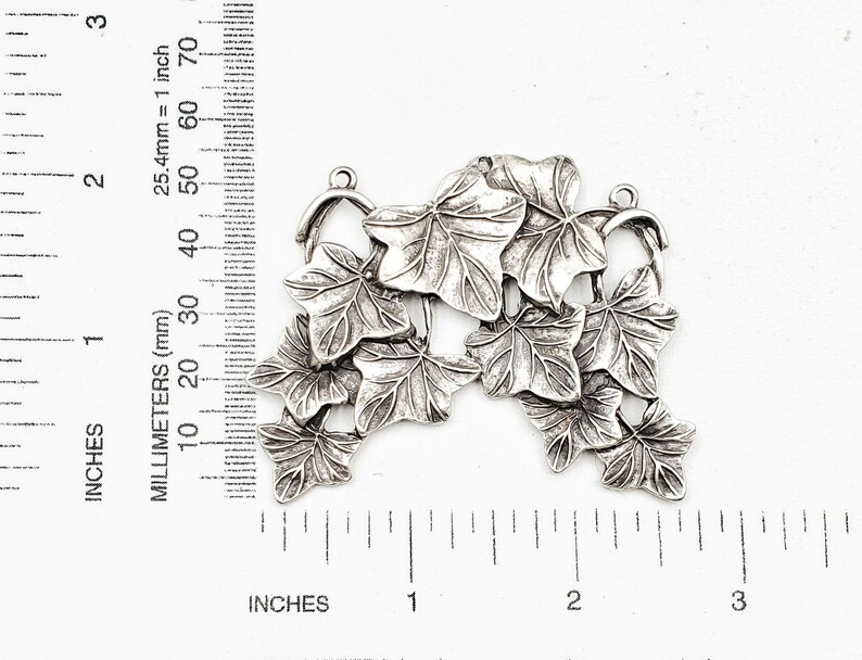 May include: Silver-toned metal charm featuring a cluster of ivy leaves. The charm is approximately 1.5 inches in length and is perfect for adding a touch of nature to jewelry or crafts.