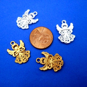 May include: Four angel charms, two gold and two silver, with intricate filigree designs. The charms are displayed on a blue background with a US penny for scale.