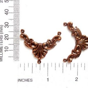 May include: Two antique copper-colored metal corner embellishments with a decorative floral design. Each piece has three holes for attaching to a project.