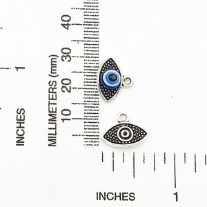 May include: Two silver evil eye charms with blue and black enamel. The charms are about 1 inch long and have a loop for attaching to a necklace or bracelet.