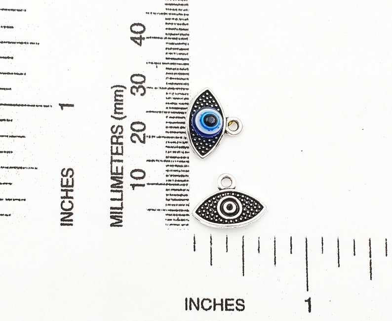 May include: Two silver evil eye charms with blue and black enamel. The charms are about 1 inch long and have a loop for attaching to a necklace or bracelet.
