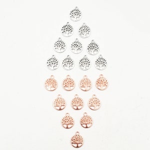 May include: A collection of silver and rose gold plated tree of life charms. The charms are arranged in a pyramid shape with the silver charms at the top and the rose gold charms at the bottom.  Antique Silver and Rose Gold Plated.
