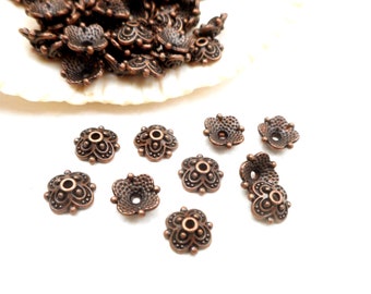 May include: A group of 10 copper-colored metal flower-shaped bead caps with a decorative design. The bead caps are about 1 cm in diameter.