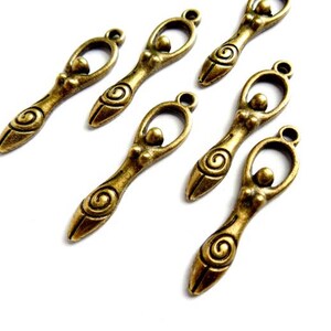 May include: Six antique gold-toned metal charms featuring a stylized female figure with a spiral design. The charms have a loop at the top for attaching to jewelry or other crafts.