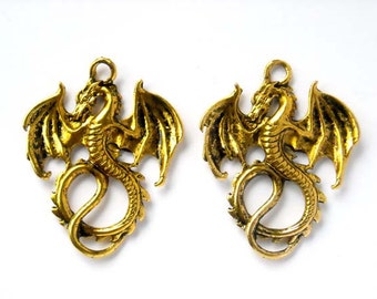 May include: Two antique gold-colored dragon pendants. Each dragon has detailed wings, a serpentine body, and a loop at the top for hanging. The dragons are facing opposite directions, perfect for jewelry making or fantasy-themed crafts.