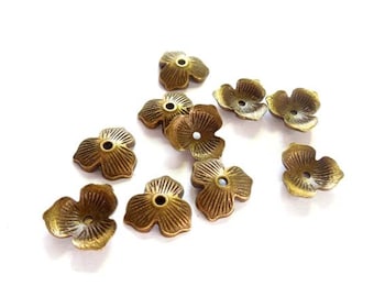Può includere: Una collezione di dieci perline di metallo color oro a forma di fiore con un foro al centro. Le perline hanno una superficie testurizzata e sono perfette per la creazione di gioielli o per l'artigianato.