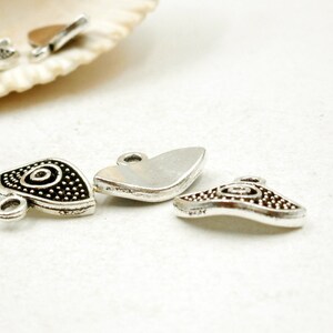 May include: Silver charm pendants with a swirl design. The charms have a silver finish and a black swirl design. The charms are perfect for adding a touch of style to your jewelry.