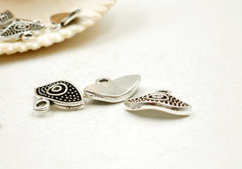 May include: Silver charm pendants with a swirl design. The charms have a silver finish and a black swirl design. The charms are perfect for adding a touch of style to your jewelry.