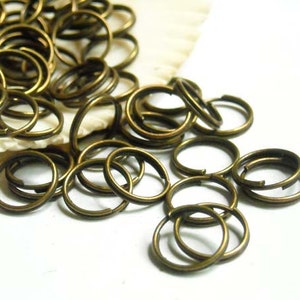 May include: A large pile of antique brass jump rings. The rings are all different sizes and are arranged in a random pattern.