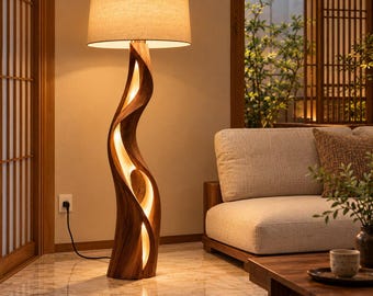 Könnte beinhalten: Eine Stehlampe mit einem hohen, skulpturalen Holzsockel in fließendem, gedrehtem Design und integrierter warmer Beleuchtung. Die Lampe hat einen großen, zylindrischen beigen Stoffschirm, der ein sanftes Licht abgibt.