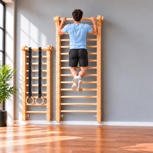May include: A tall wooden wall-mounted ladder unit with horizontal rungs, featuring a second smaller ladder unit beside it equipped with two black hanging gymnastic rings. The structure is made of light-colored wood with a natural finish.