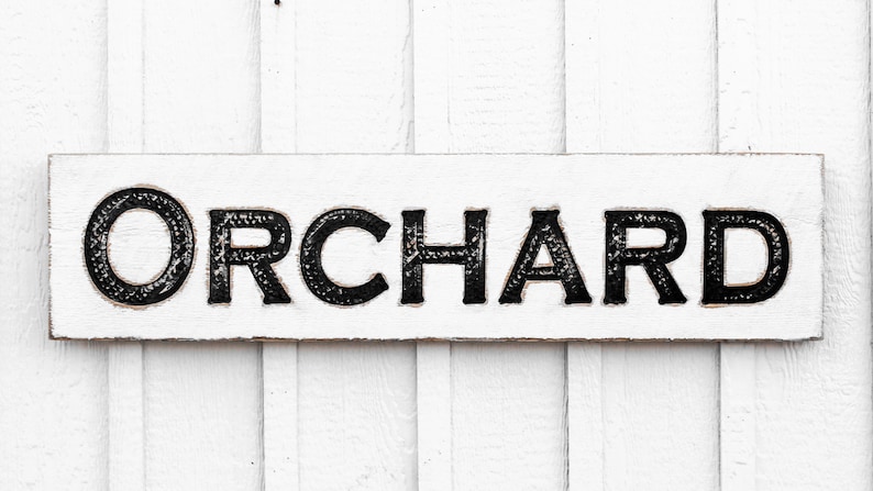 May include: White wooden sign with black lettering that reads "ORCHARD".