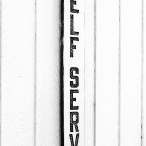 May include: A white wooden sign with black lettering that reads "SELF SERVE".