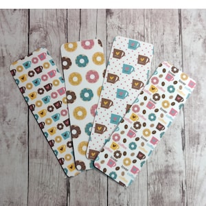 May include: Four different bookmark designs featuring coffee cups, donuts, and coffee beans. The bookmarks are white with pink, blue, and brown accents. The text on the bookmarks reads "coffee lover".