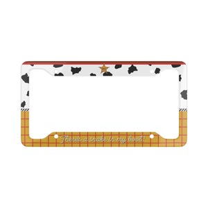 Puede incluir: Marco de matrícula con fondo blanco con manchas negras de vaca, una estrella dorada y la frase "There's a snake in my boot!". El marco tiene un borde rojo y un patrón de cuadrícula amarilla y roja.