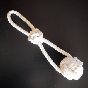 May include: White cotton rope dog toy with two knots. The toy is designed for dogs to chew and play with.