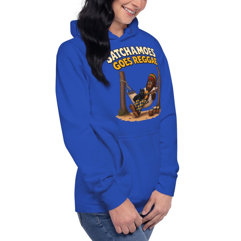 K&ouml;nnte beinhalten: Ein k&ouml;nigsblauer Kapuzenpullover mit einem Grafikdruck, der eine Figur in einer H&auml;ngematte mit einer schwarzen Katze zeigt. Der Text &uuml;ber der Illustration lautet SATCHAMOES GOES REGGAE in gelben Buchstaben. Die Figur tr&auml;gt einen Hut.