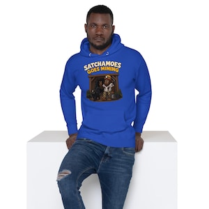 May include: A royal blue hooded sweatshirt featuring a graphic print of a creature in a mine entrance with a black cat. The text above the illustration reads SATCHAMOES GOES MINING in yellow letters. The hoodie has long sleeves and a front pocket.
