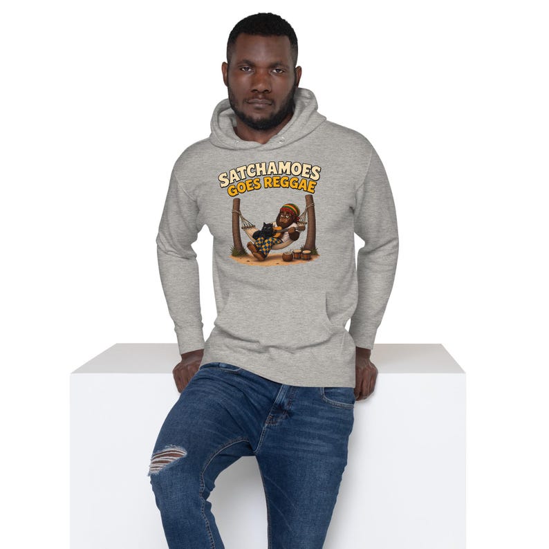 K&ouml;nnte beinhalten: Ein hellgrauer Kapuzenpullover mit einem Grafikdruck, der eine Figur in einer H&auml;ngematte mit einer Katze und den Text SATCHAMOES GOES REGGAE zeigt. Der Hoodie hat lange &Auml;rmel, eine K&auml;ngurutasche vorne und eine Kapuze mit Kordelzug.