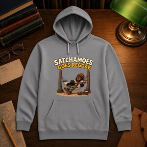 K&ouml;nnte beinhalten: Ein grauer Kapuzenpullover mit einem Grafikdruck eines Gorillas, der eine M&uuml;tze in Rastafarifarben tr&auml;gt und mit einer schwarzen Katze in einer H&auml;ngematte Gitarre spielt. Der Text &uuml;ber der Illustration lautet SATCHAMOES GOES REGGAE in Gelb und Wei&szlig;.