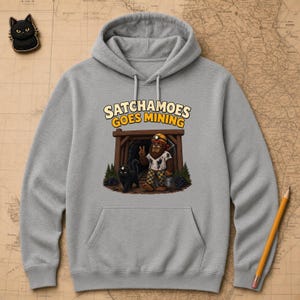 May include: A heather grey hooded sweatshirt featuring a graphic of a brown creature wearing a yellow hard hat and chequered trousers, standing in a mine entrance with a black cat. The text above reads SATCHAMOES GOES MINING in yellow and white.