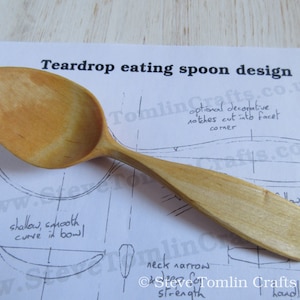 Puede incluir: Una cuchara de madera con forma de lágrima y un mango ancho. La cuchara está apoyada sobre un papel con un dibujo de la cuchara e instrucciones para hacerla. El texto en el papel dice "Teardrop eating spoon design" y "Steve Tomlin Crafts 2019".