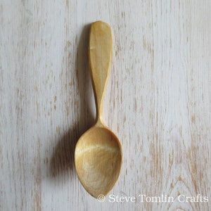 May include: A wooden spoon with a natural finish. The spoon has a long handle and a rounded bowl.
