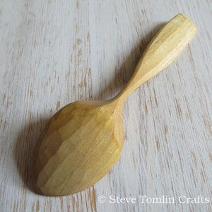 May include: A wooden spoon with a natural finish. The spoon has a rounded bowl and a long, slender handle.
