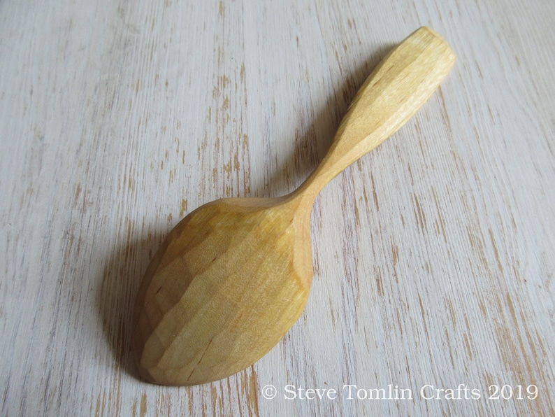 May include: A wooden spoon with a natural finish. The spoon has a rounded bowl and a long, slender handle.