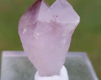 May include: A pale purple amethyst crystal with a double termination, also known as a double-pointed crystal. The crystal is clear and has a slight pink hue.