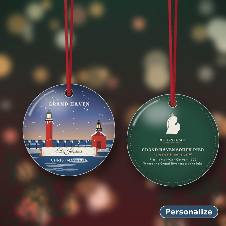 May include: Two round ceramic ornaments with red hanging ribbons. The left ornament shows a Grand Haven lighthouse scene with text "The Johnsons" and "CHRISTMAS 2026". The right ornament is green with a Michigan map, "MITTEN TRAILS", and "GRAND HAVEN SOUTH PIER" text.