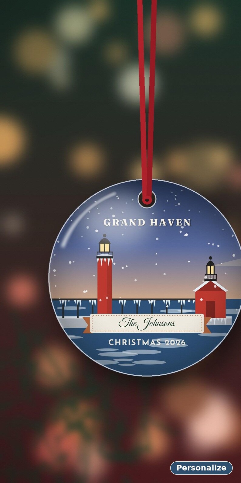 May include: A round, flat Christmas ornament hanging from a red ribbon. The design features a winter scene with the Grand Haven lighthouse, a pier, and snow. It includes the text 'GRAND HAVEN', 'The Johnsons', and 'CHRISTMAS 2026'.