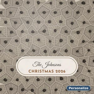 May include: A rectangular sign featuring a beige background with a repeating pattern of gray geometric cells, each containing a dark center dot. A central white label displays the text The Johnsons CHRISTMAS 2026. A small blue button says Personalize.