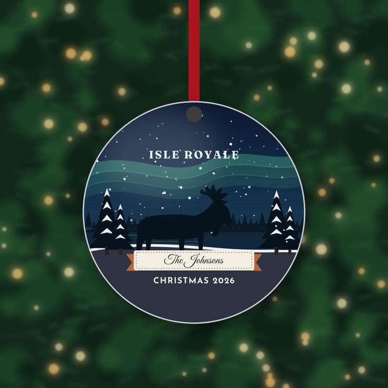 May include: A round Christmas ornament featuring a dark blue night sky with a green aurora, a silhouette of a moose, and pine trees. Text reads ISLE ROYALE, The Johnsons, and CHRISTMAS 2026. It hangs from a thin red ribbon.