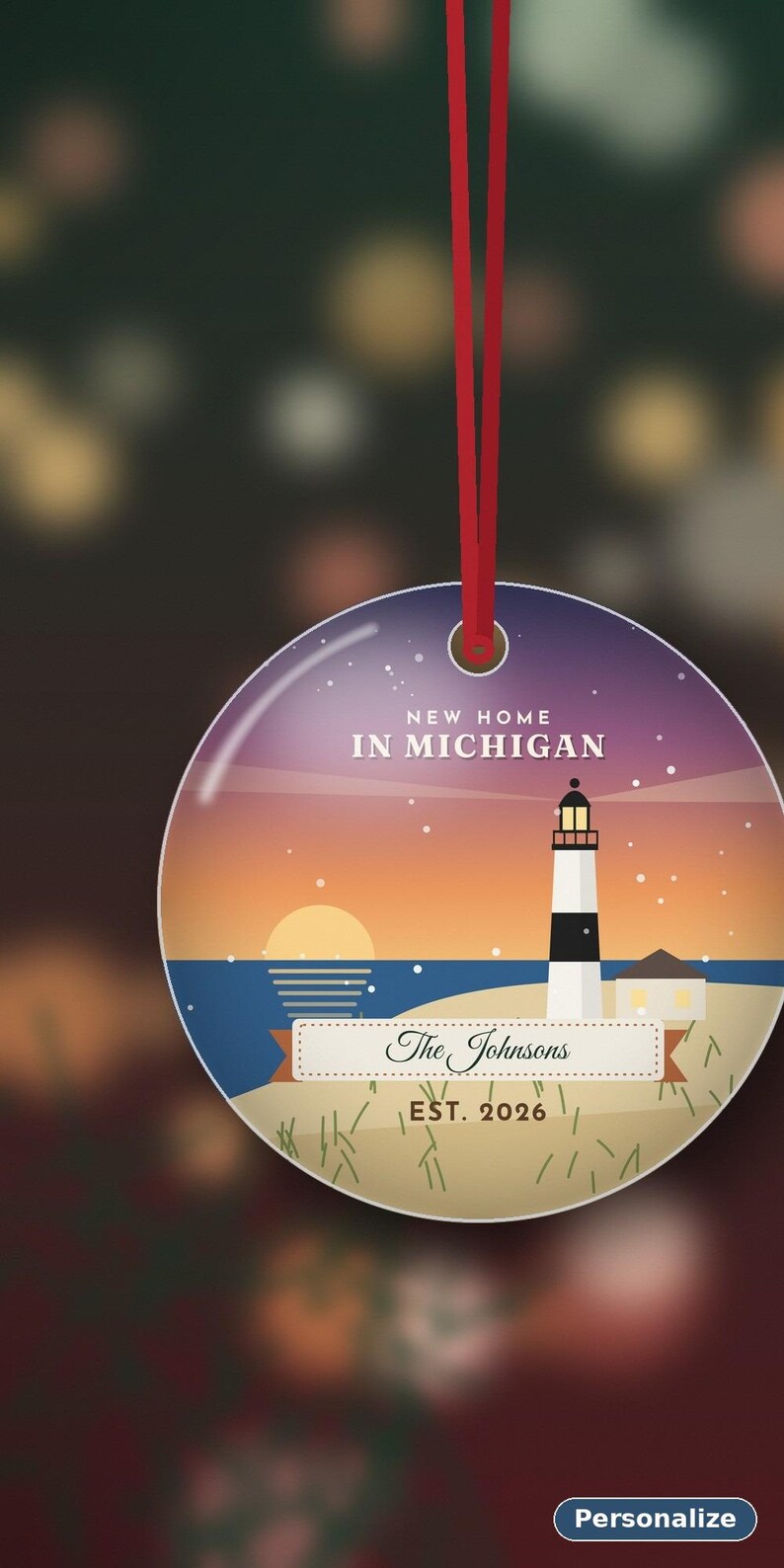 K&ouml;nnte beinhalten: Ein runder, flacher H&auml;ngeschmuck mit einer Leuchtturm-Illustration bei Sonnenuntergang. Der Text lautet NEW HOME IN MICHIGAN, The Johnsons und EST. 2026. Das Design zeigt einen Strand, ein dunkelblaues Meer und einen violetten Sternenhimmel. Ein rotes Band ist befestigt.