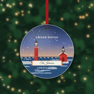 May include: A round Christmas ornament featuring a red lighthouse and pier in Grand Haven during a snowy night. The design includes the text Grand Haven, The Johnsons, and Christmas 2026. A red ribbon is attached to the top for hanging.