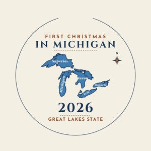 May include: A circular graphic design featuring the text FIRST CHRISTMAS IN MICHIGAN in dark blue and brown. A blue map of the Great Lakes with labels is centered, accompanied by a compass rose, the year 2026, and the text GREAT LAKES STATE.