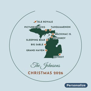 May include: A circular ornament featuring a dark green map of Michigan on a light blue background. It marks locations like Isle Royale, Pictured Rocks, and Detroit with orange dots. Text reads The Johnsons, CHRISTMAS 2026, and Personalize.