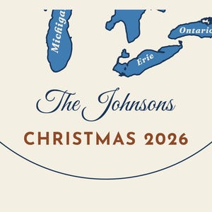 May include: A circular ornament featuring blue illustrations of Lake Michigan, Lake Erie, and Lake Ontario. The text reads The Johnsons in a dark blue script font and CHRISTMAS 2026 in a bold brown sans-serif font on a cream background.