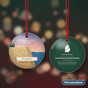 Puede incluir: Dos adornos redondos de cer&aacute;mica con cintas rojas. El adorno izquierdo muestra Sleeping Bear Dunes, "The Johnsons" y "Christmas 2026". El derecho es verde oscuro con un mapa blanco de Michigan y detalles de texto.