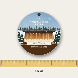 May include: A round ornament featuring a graphic illustration of Tahquamenon Falls with pine trees, snow, and the text 'The Johnsons' and 'CHRISTMAS 2026'. A ruler below shows the ornament has a diameter of 3.5 inches.