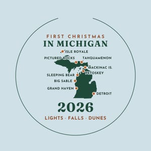 May include: A circular ornament featuring a dark green map of Michigan on a light blue background. Text reads FIRST CHRISTMAS IN MICHIGAN 2026 LIGHTS FALLS DUNES. Orange dots mark locations including Isle Royale, Pictured Rocks, and Detroit.