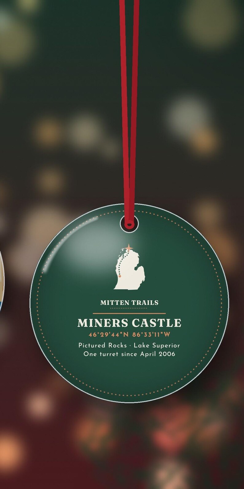 K&ouml;nnte beinhalten: Ein runder, dunkelgr&uuml;ner Anh&auml;nger an einem roten Band. In der Mitte befindet sich eine wei&szlig;e Karte von Michigan mit einem Stern, der Text MITTEN TRAILS, MINERS CASTLE, die Koordinaten 46&deg;29'44"N 86&deg;33'11"W, Pictured Rocks, Lake Superior und One turret since April 2006.
