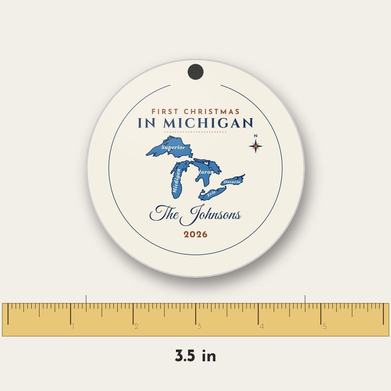 May include: A round white ceramic ornament measuring 3.5 inches in diameter. It features a blue map of the Great Lakes, a compass rose, and the text: First Christmas in Michigan, The Johnsons, and 2026. A small hole is at the top.