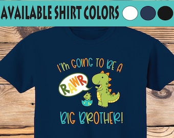 May include: A navy blue t-shirt with a green dinosaur graphic and the text "I'm going to be a RAWr BIG BROTHER!"