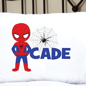 May include: White pillowcase with a red and blue cartoon Spiderman character, a black spider in a white web, and the name "CADE" in blue letters.