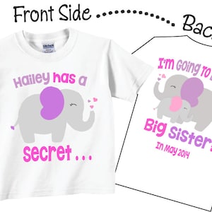 Puede incluir: Camiseta blanca con un elefante rosa y el texto "Hailey has a secret..." en la parte delantera. La parte posterior de la camiseta tiene dos elefantes rosas y el texto "I'm going to be a Big Sister! In May 2014."